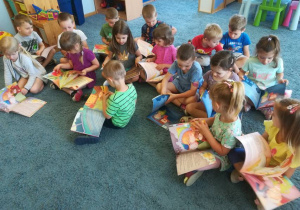 Dzieci na dywanie oglądają otrzymane książki.